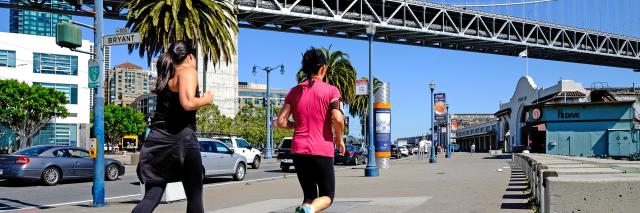 Joggers and pedestrians on the Embarcadero pass under the Bay Bridge on a sunny day in 2014