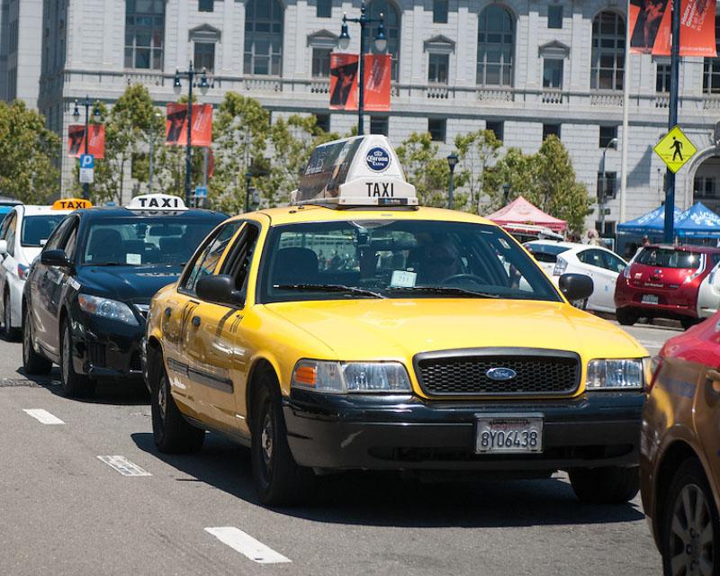 a row of taxis along Polk Street with the state office building in the background