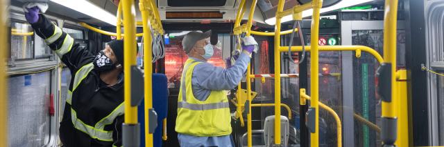 Car cleaners wearing masks and disinfecting a bus