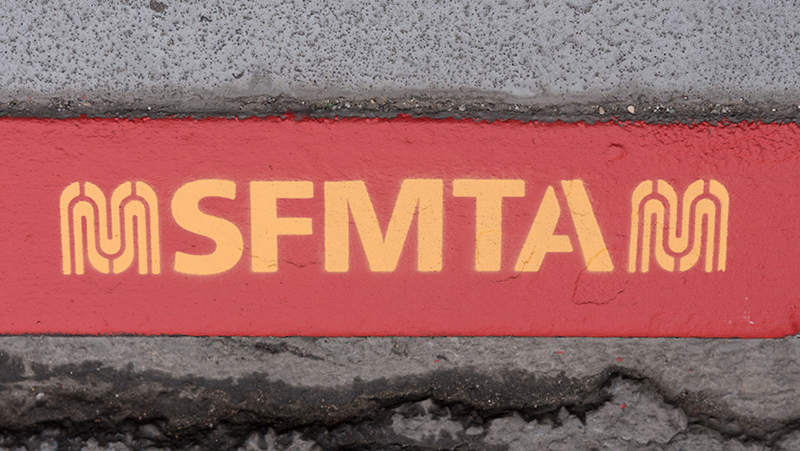 Painted red curb with a stencil that says "SFMTA"