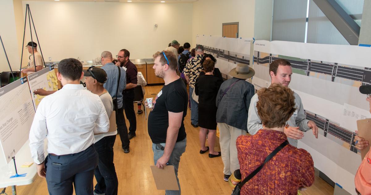 Image shows members of the public engaging with Geary Rapid Project staff at the project's Open House. 