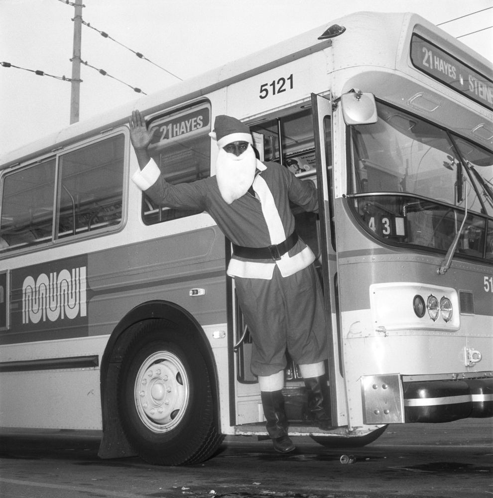a person dressed as santa claus waves from a Muni bus