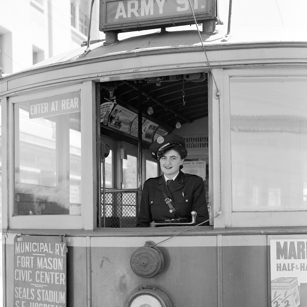 A woman wearing a muni uniform at the controls of a streetcar