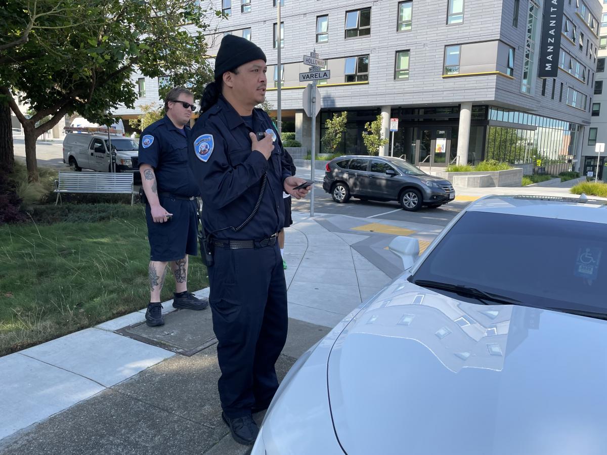 Two San Francisco Parking Control Officers inspect a vehicle on the side of the road.