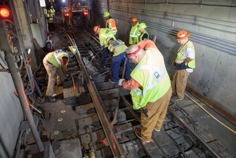 Photo of group of people lifting rail with a jack and pry bars