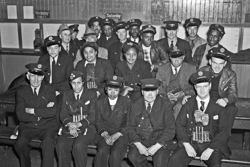 Black and white photo of a group of a male and female operators and conductors from a variety of racial backgrounds posing in four rows