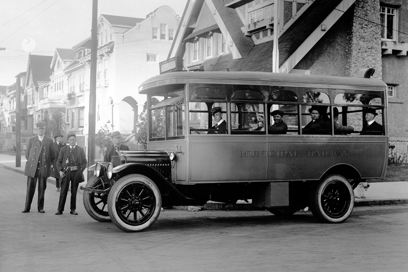 An early Municipal Railway bus at 10th Avenue and Fulton Street in 1917.  People are aboard the bus looking out the window towards the camera and two men stand in front of the bus.