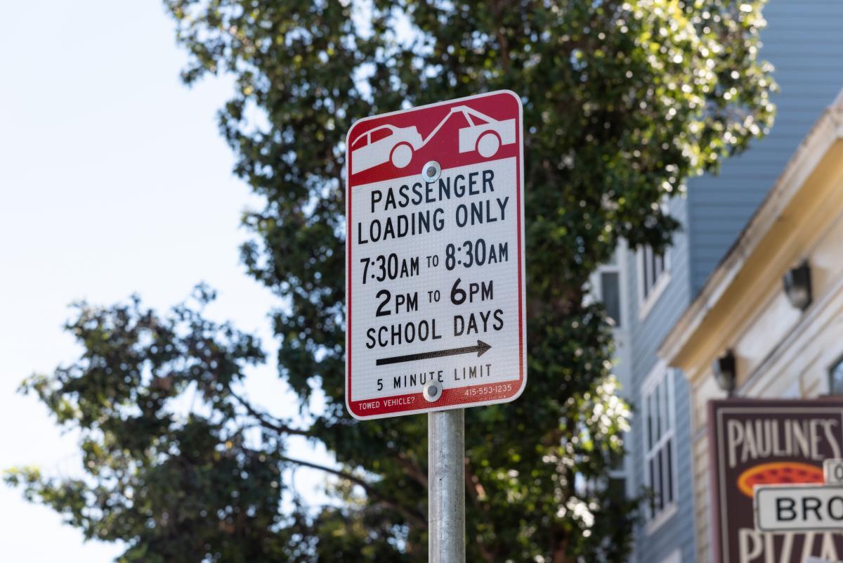Passenger loading sign in front of building and trees