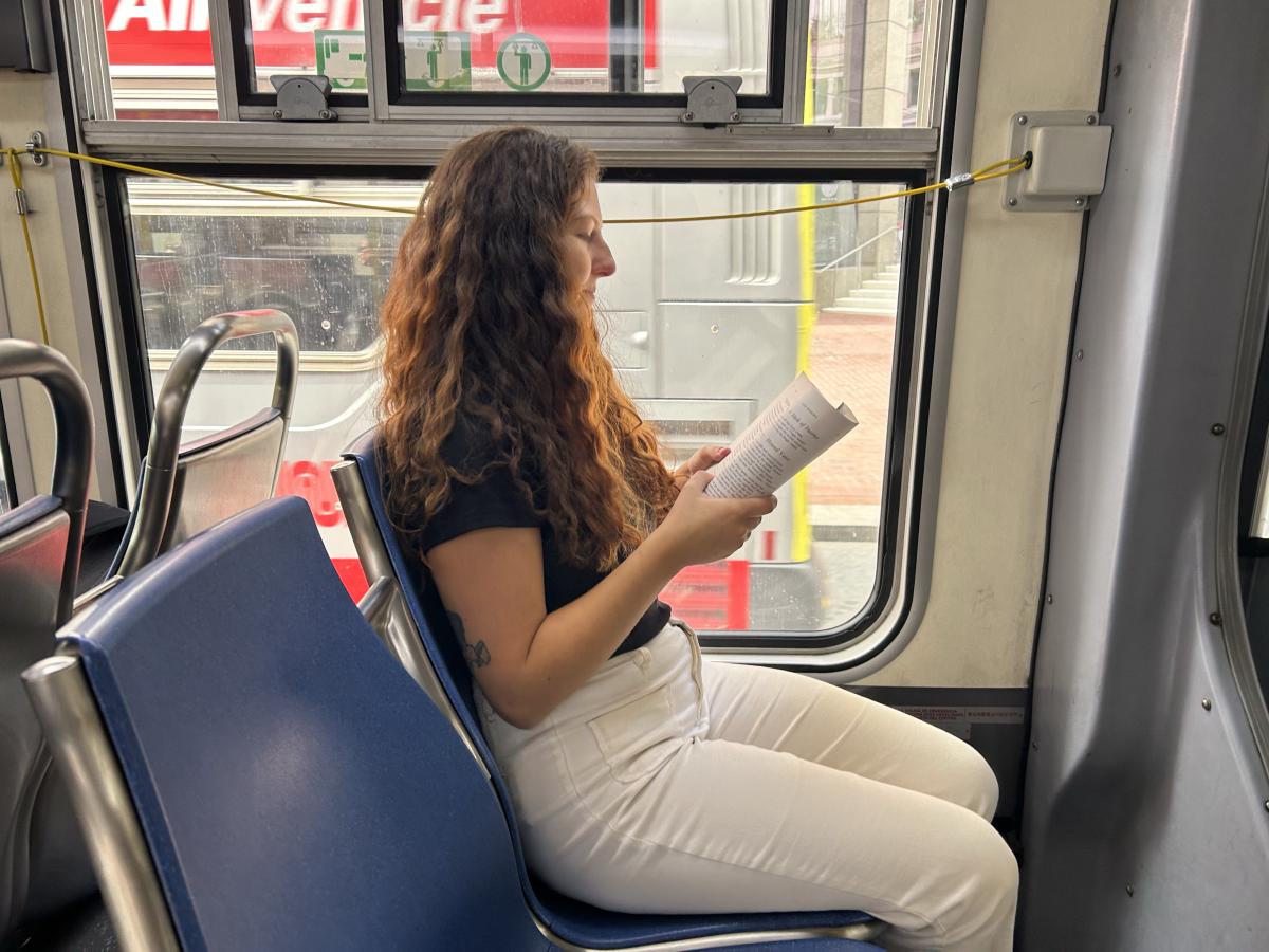 A woman reading while sitting on a bus.
