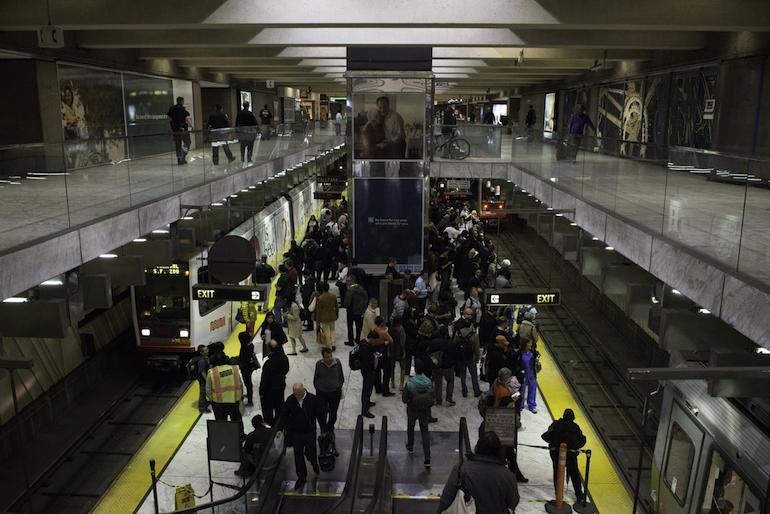 Crowded subway platform at Embarcadero Station with passengers and staff during large event.