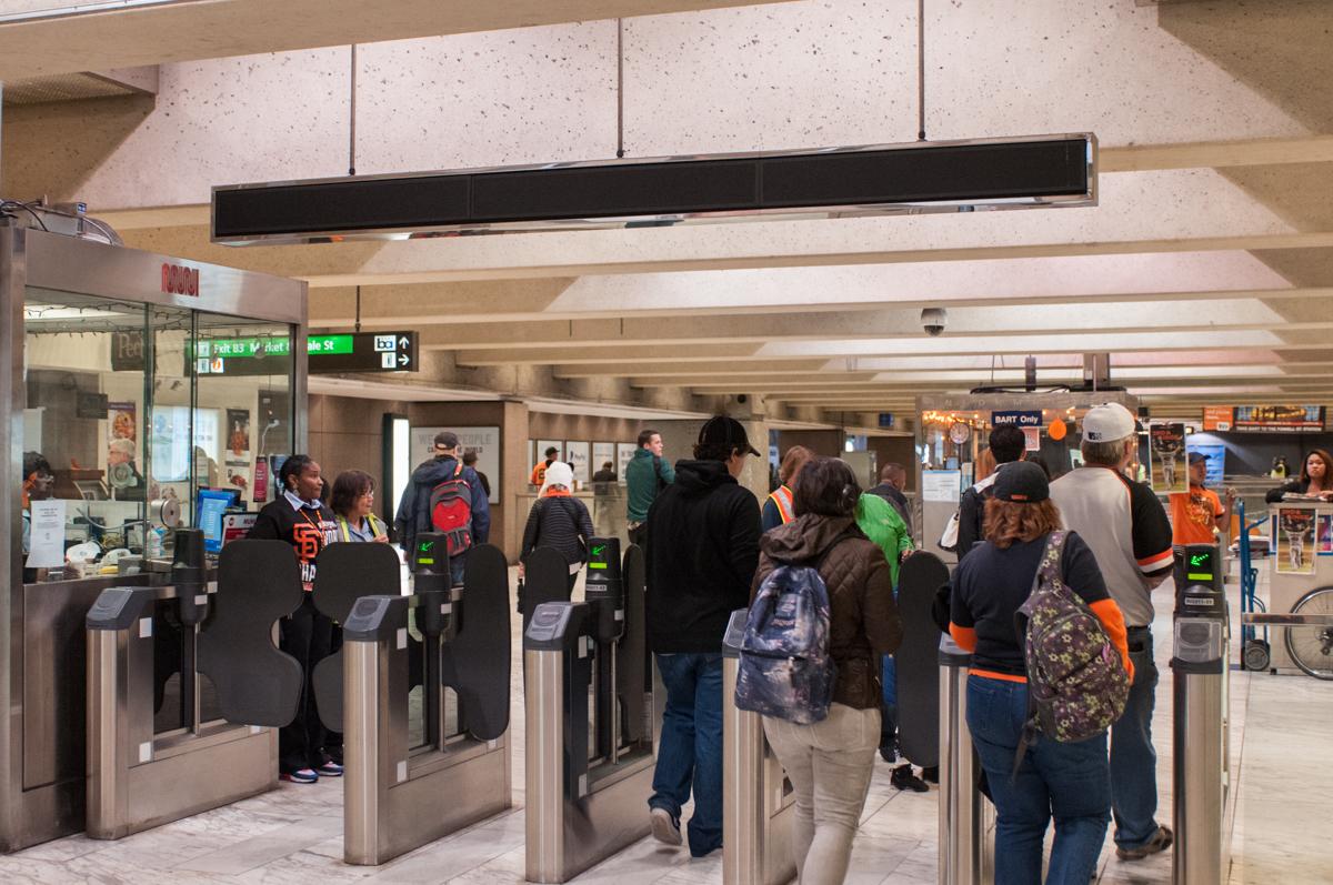 Commuters and fans pass through fare gates at a crowded transit station.
