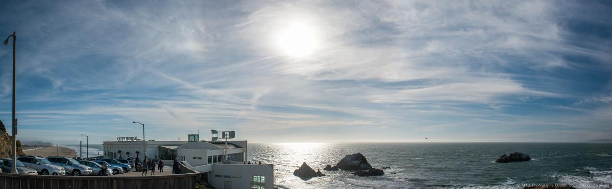 Cliff House building overlooking Pacific Ocean with rocky outcrops and Ocean Beach visible under cloudy sky