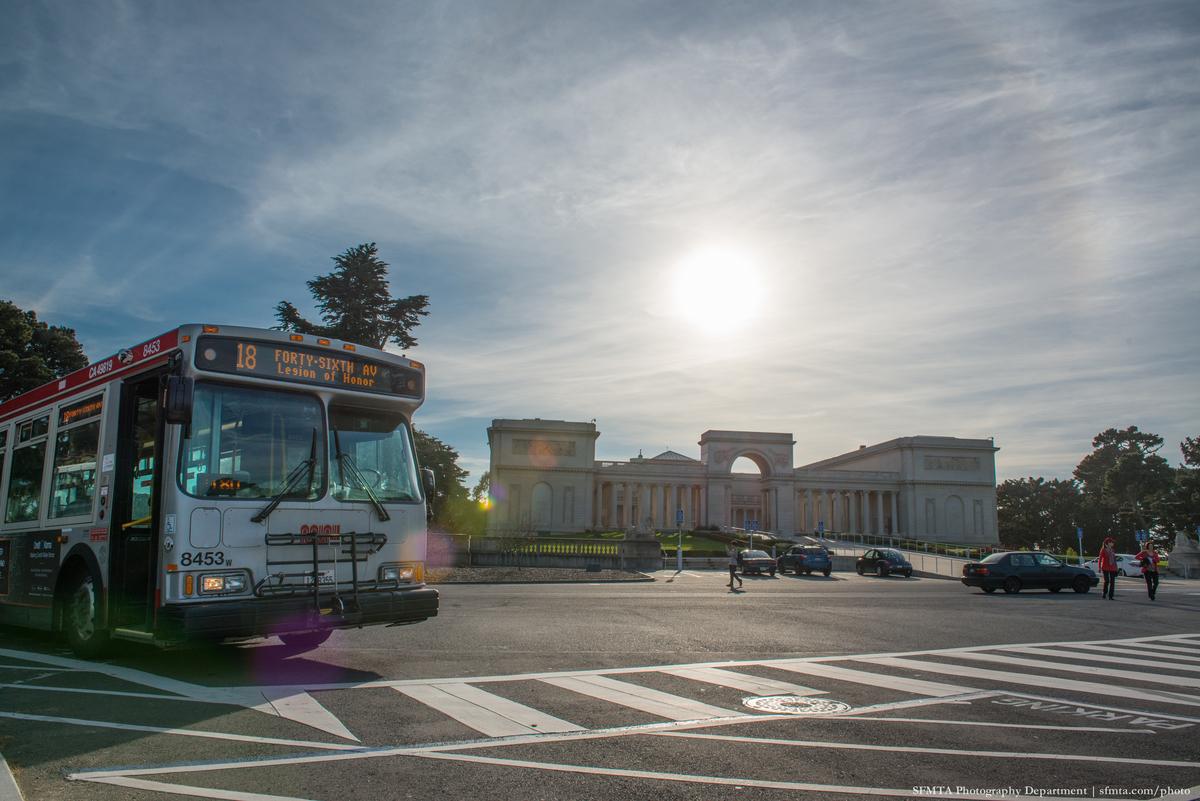 Muni bus 18 stopped at crosswalk in front of the Legion of Honor museum building.