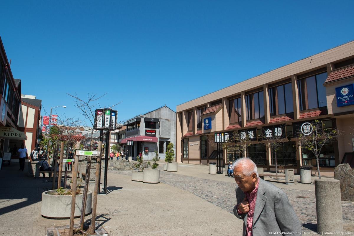 Japantown Peace Plaza with traditional Japanese architecture, storefronts, and pedestrians on a clear day.