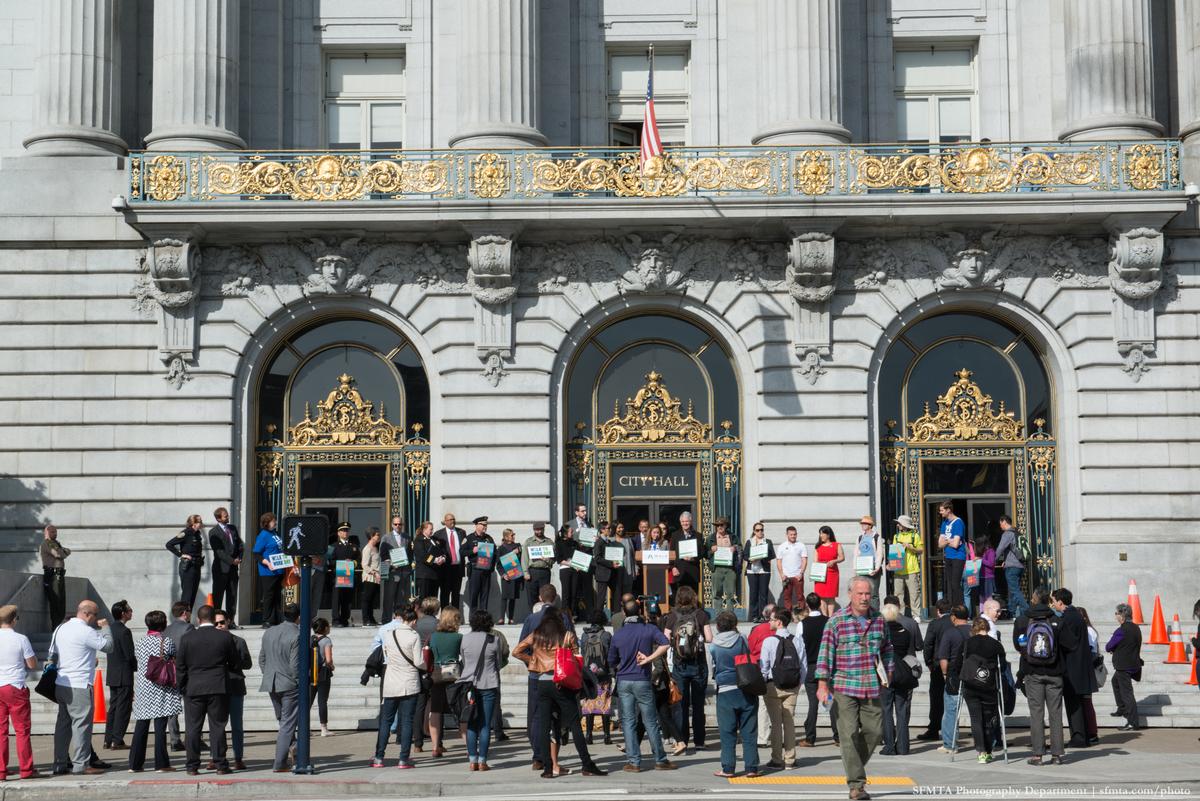 Crowd gathered on Polk Street steps at City Hall with dignitaries at podium during Walk to Work Day event.