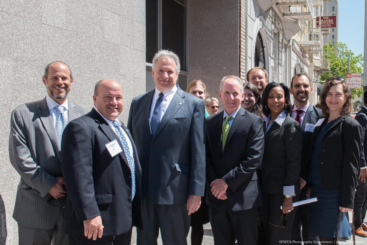 Group of transit officials posing together on a city street during a walking tour.