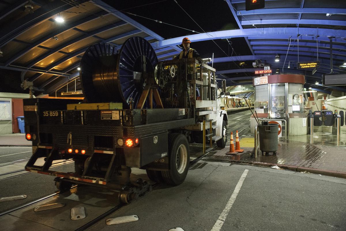 Specialized rail truck with large spools enters tunnel at West Portal Station during transit service work.