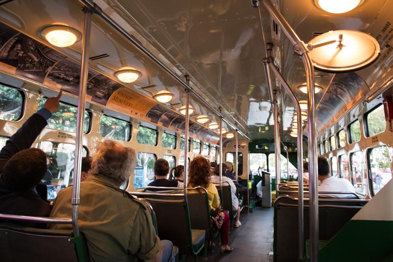 Interior of vintage trolley coach with seated passengers and overhead lighting