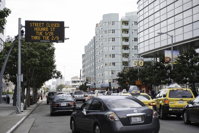 Electronic street sign displaying Howard Street closure dates from Tuesday 1/26 through Tuesday 2/9, with cars and taxis on 4th Street below.