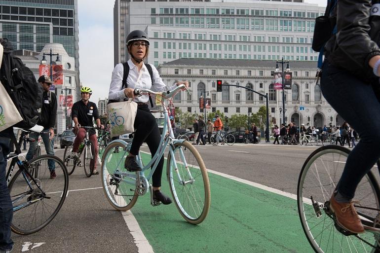 Cyclists ride on a green bike lane near City Hall during Bike to Work Day.