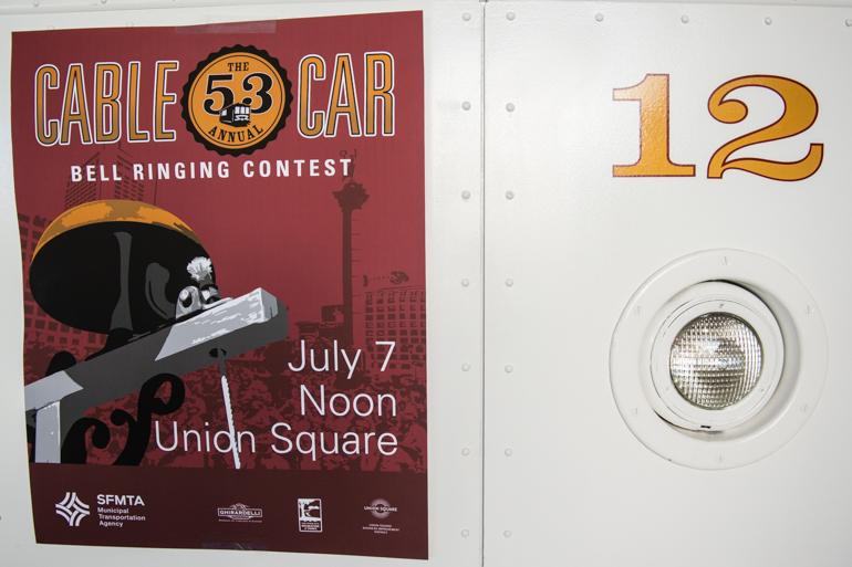 Cable Car 12 headlamp with gold number 12 and maroon Bell Ringing Contest poster displayed on white exterior.
