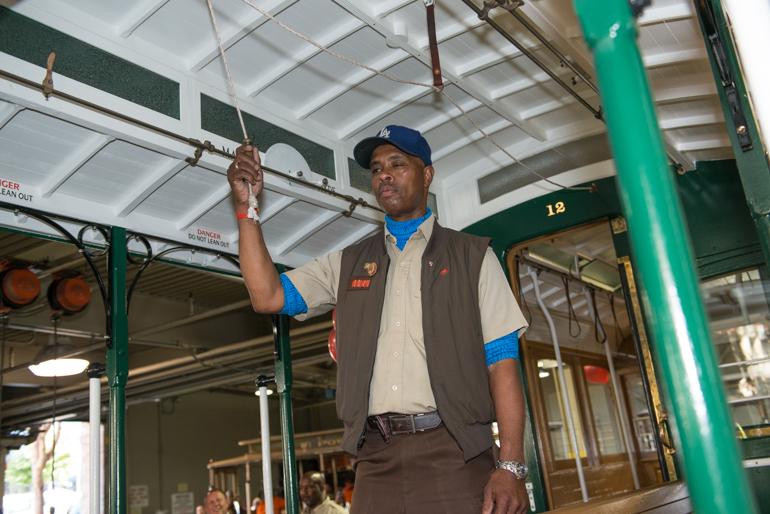 Cable car operator in uniform ringing bell inside historic San Francisco cable car station.