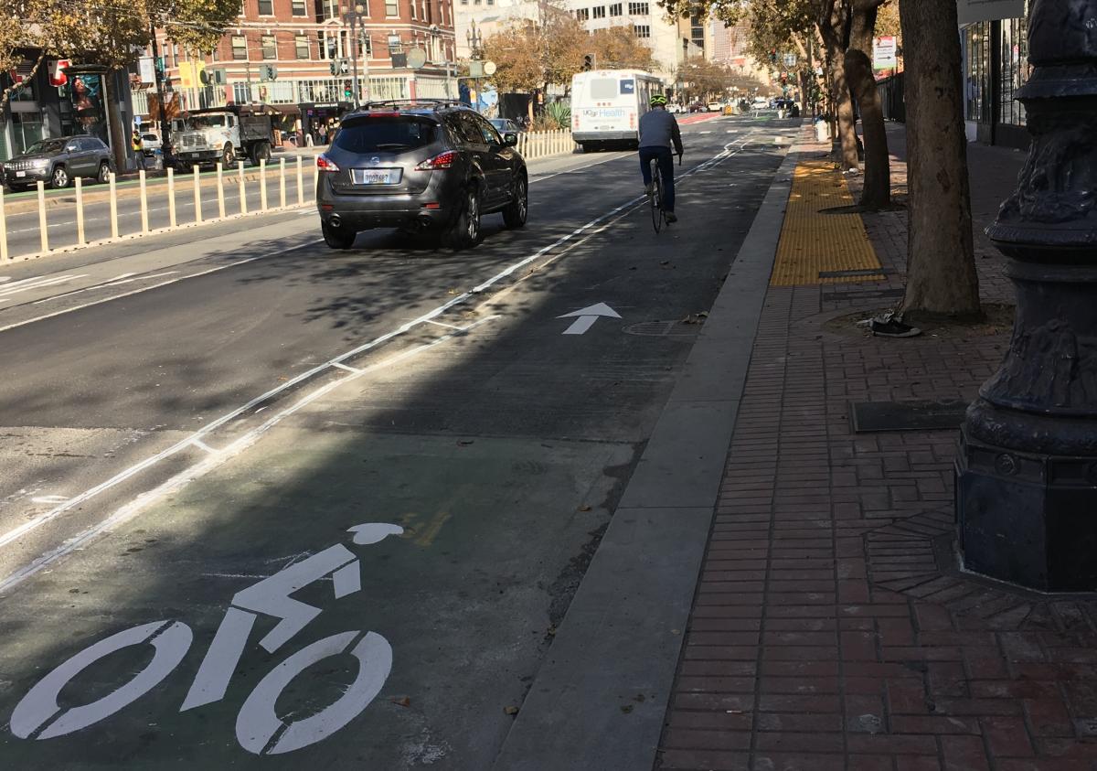Bike lane markings on Market Street with cyclist riding and parked car visible