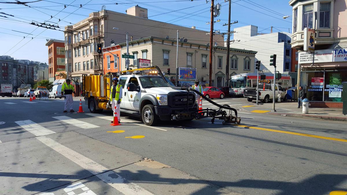 Street maintenance crew operating grinding equipment on Mission Street intersection