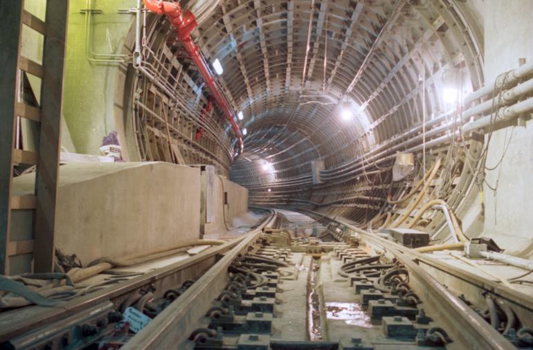 Interior view of Muni Metro Tunnel under construction showing curved track and tunnel infrastructure.
