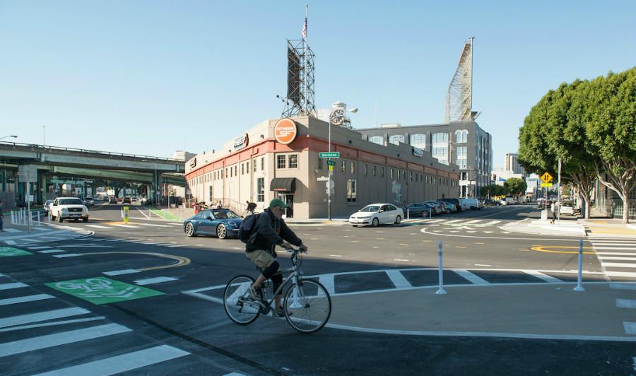Cyclist riding through protected intersection with green bike lane markings at 9th and Division in San Francisco.