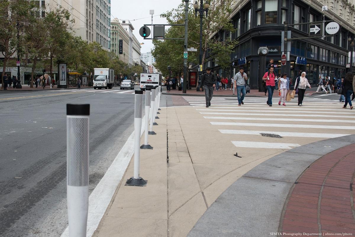 Bollard posts and crosswalk on Market Street with pedestrians crossing.