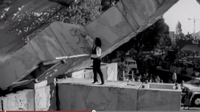 Woman standing on concrete structure at Vaillancourt Fountain with city skyline in background.