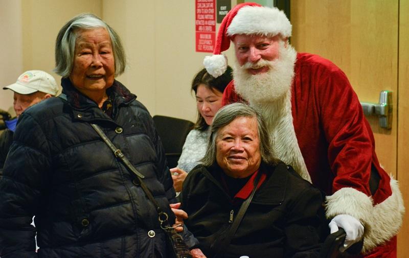 Santa Claus poses with senior women and a child at a holiday luncheon event.