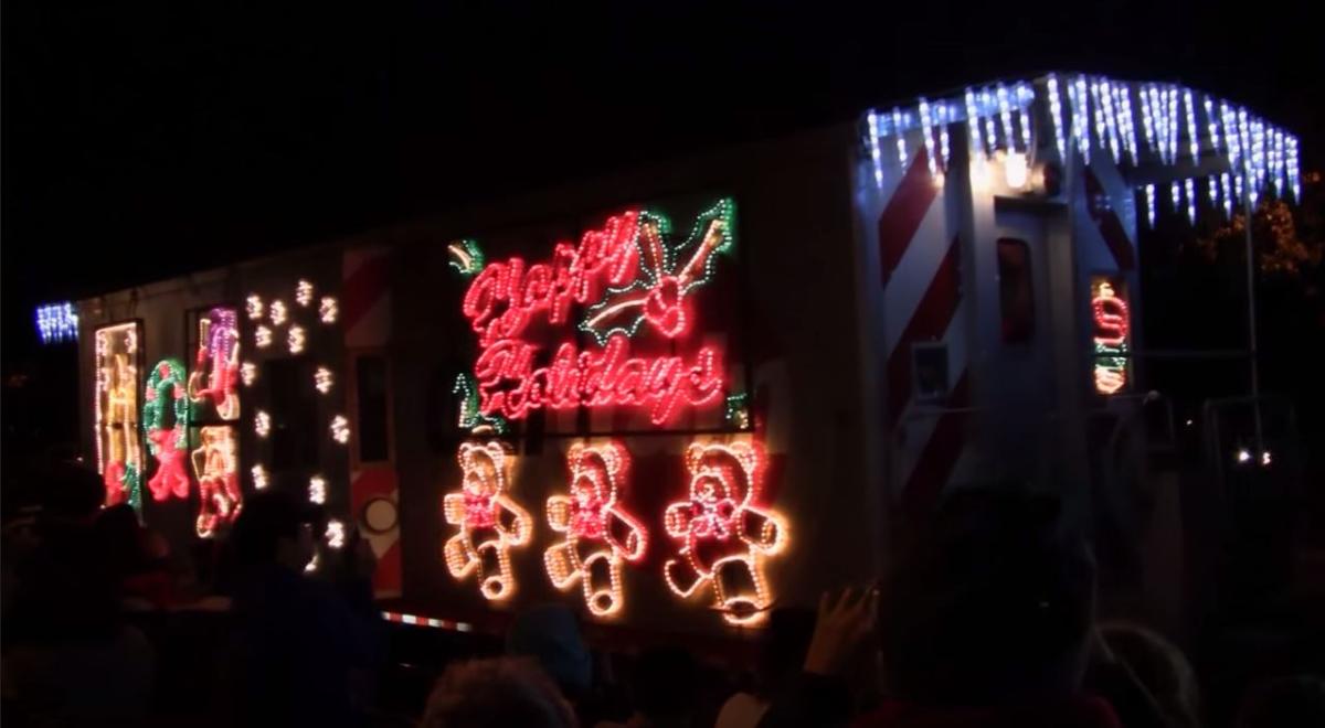 Caltrain vehicle decorated with red neon holiday lights and gingerbread man designs at night.