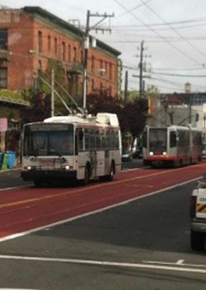Two Muni vehicles on red transit-only lanes on Church Street in San Francisco.