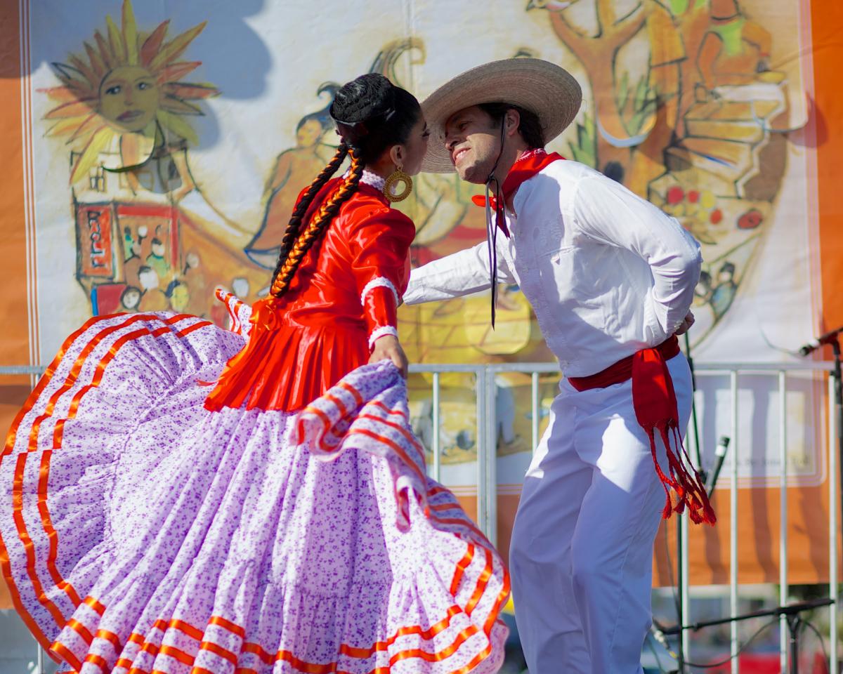 Ballet Folklorico dancers perform in traditional red and purple costumes at Cinco de Mayo Festival celebration.