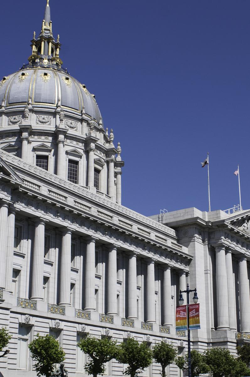 San Francisco City Hall's dome and neoclassical facade with columns against blue sky.