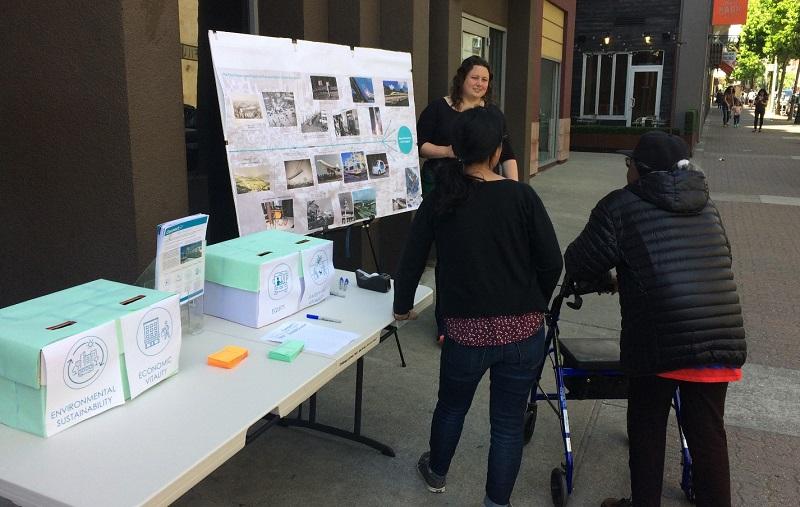 Community outreach pop-up table with survey materials and transit planning displays on San Francisco street.