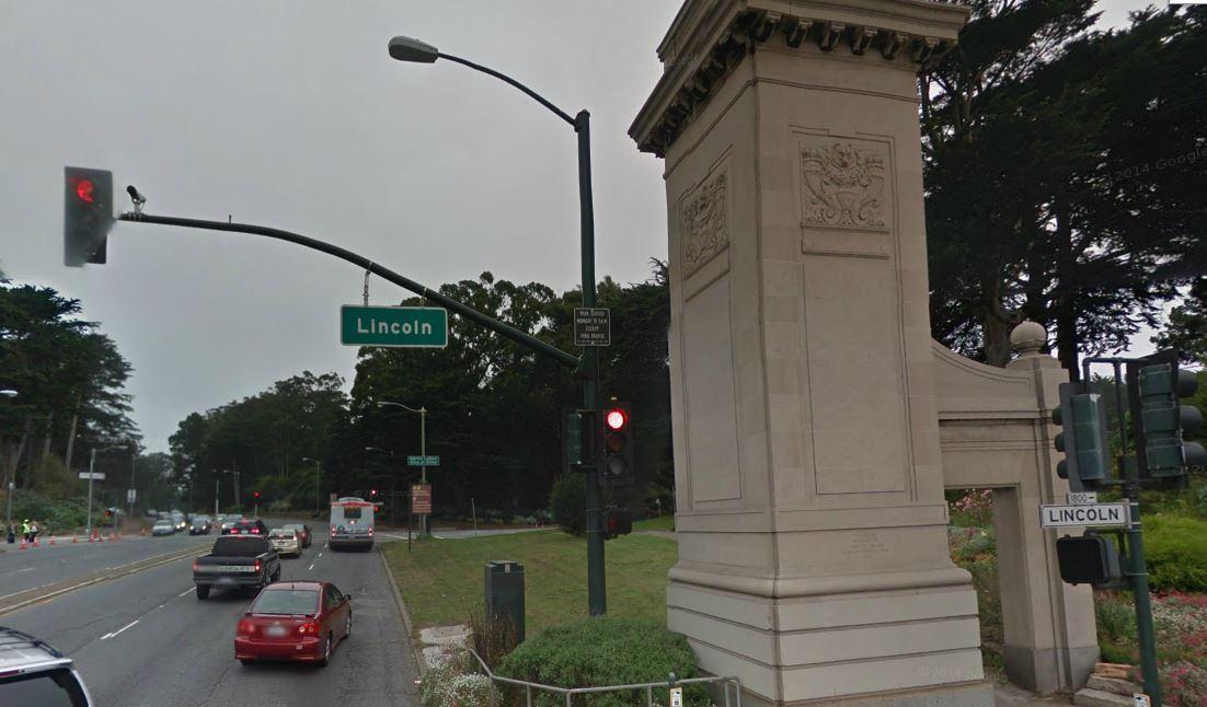 Northbound traffic on 19th Avenue at Lincoln Way with Muni bus and street monument.