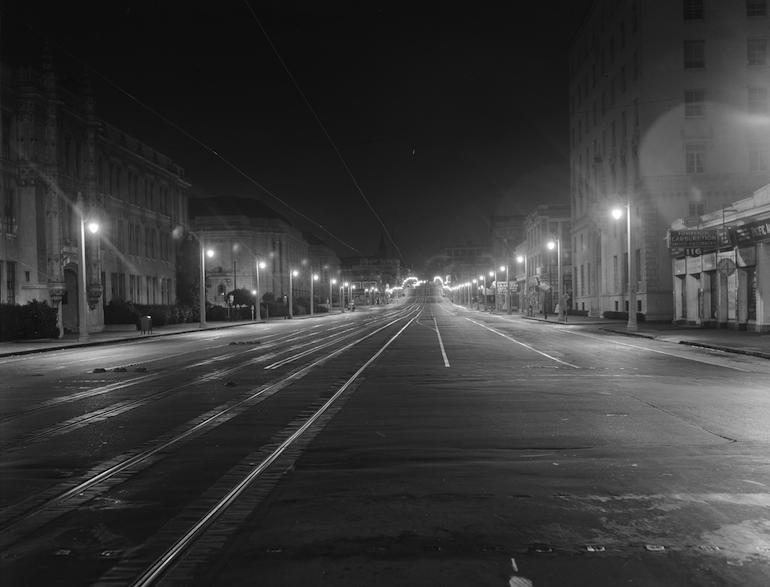 Empty street at night with streetlights and trolley tracks, Van Ness Avenue and Fell Street, 1937.