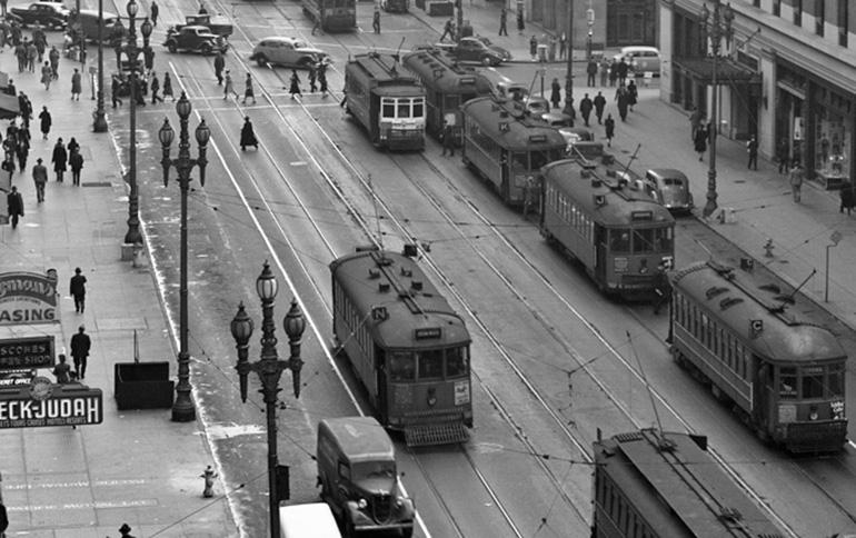 Black and white aerial view of Market Street with multiple streetcars on tracks, pedestrians, and vintage automobiles, 1940.