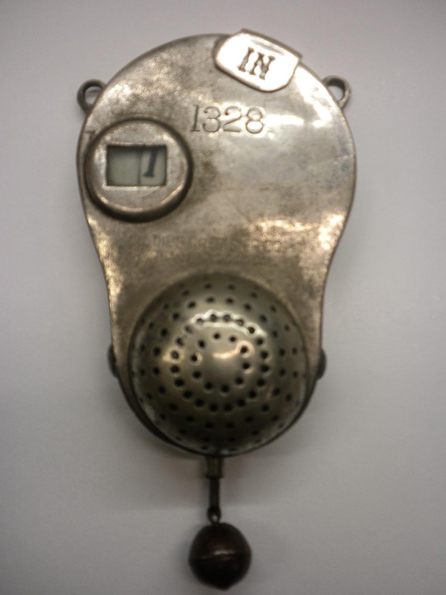 Antique portable fare register from 1828, metal device with circular dial window and perforated speaker grille.