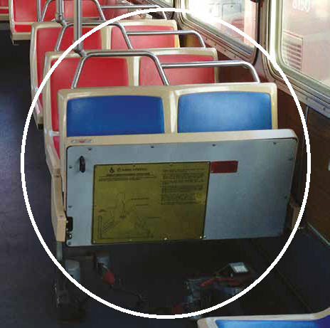 Forward-facing seats in flipped-up position on Muni bus with safety information placard visible.