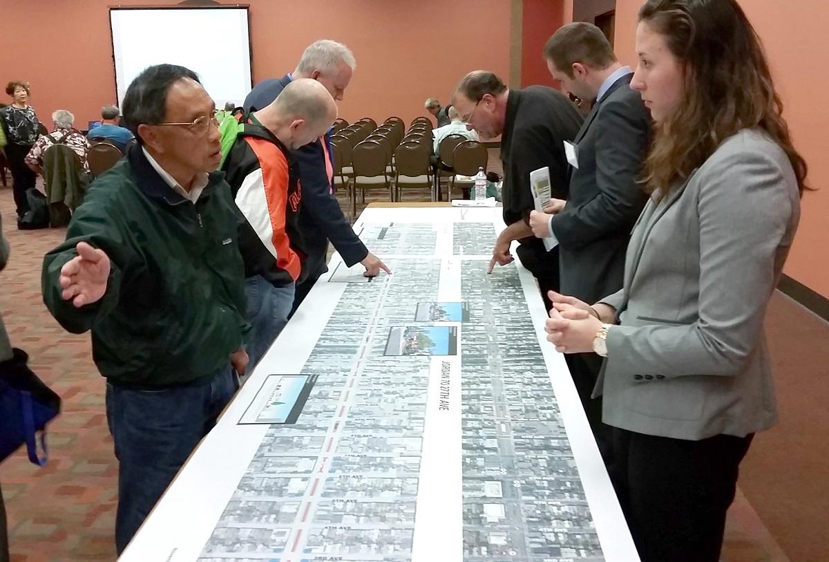 Community members and project staff review large street diagrams at a public meeting about the Geary BRT project.