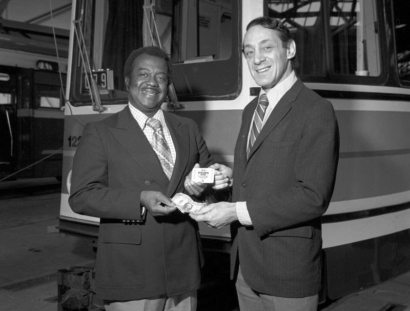 Two men in suits exchanging transit passes in front of a streetcar, 1978.