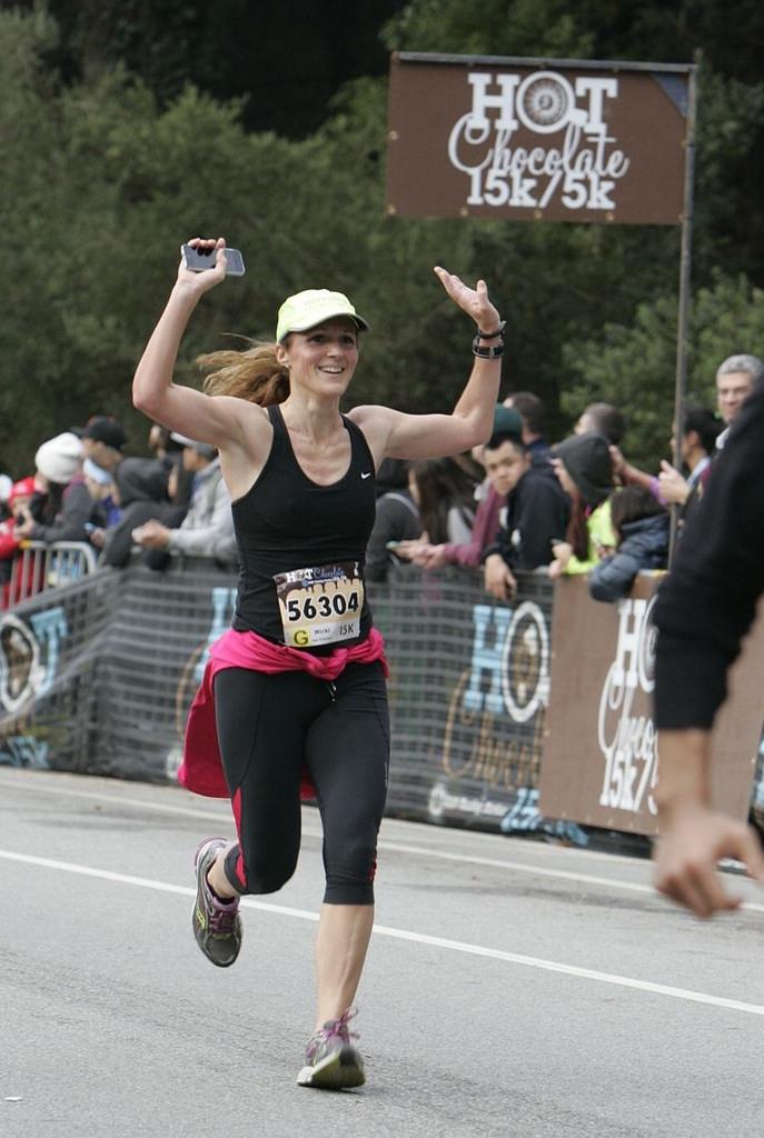 Runner with raised arms crossing finish line at Hot Chocolate 15K/5K race in Golden Gate Park.