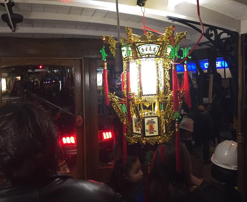 Ornate gold, red and green lantern displayed inside a motorized cable car during Chinese New Year Parade.