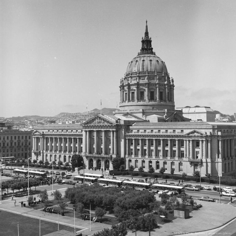 San Francisco City Hall with dome and classical columns, plaza with trees and parked buses, 1969.