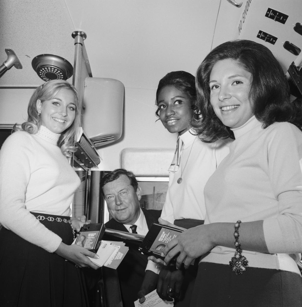 Four people examine stereo music system equipment inside a coach at Presidio Yard, 1969.