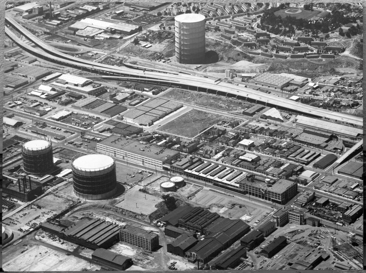Aerial view of Dogpatch neighborhood with 280 freeway, industrial buildings, and storage tanks, 1974.
